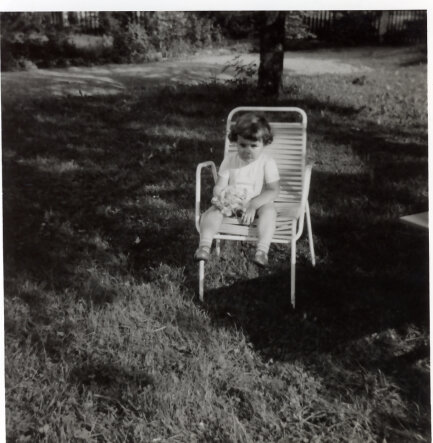Kleinkind sitzt auf Gartenstuhl